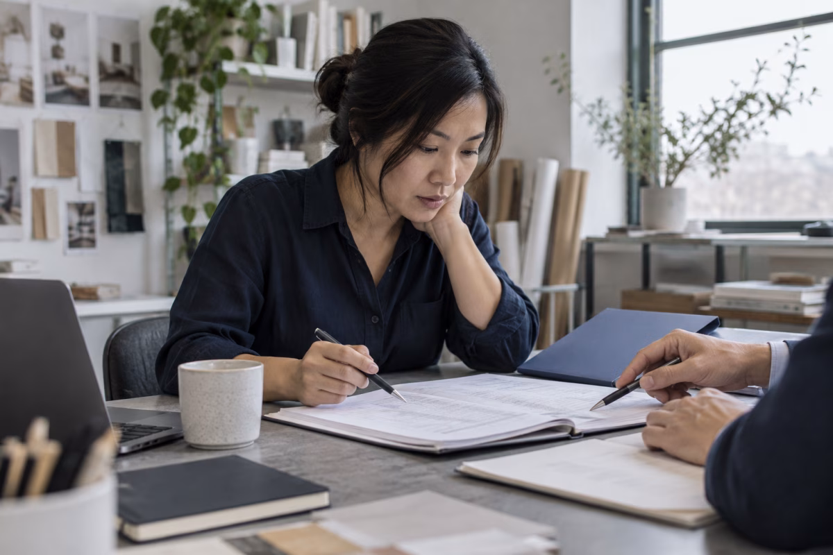 A business owner reviews financial records with an advisor in a creative studio.